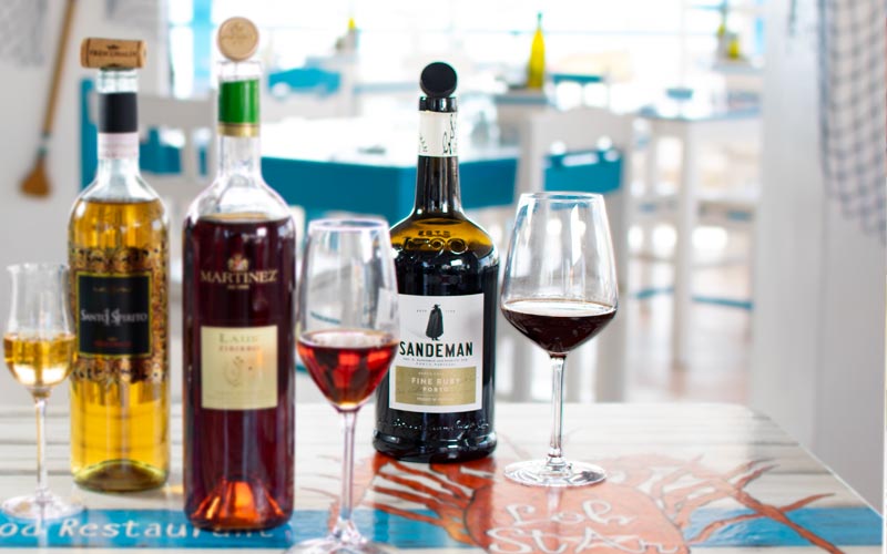 PalmBeach Tropical Restaurant | Porto Fine Ruby DOC Sandeman <small>(by the glass)</small>
 | Vol. 19,5% / Touriga Franca, Tinta Roriz, Tinta Amarela, Tinta Barroca, Tinto Cão / DOC Porto / Portugal, Douro / Clear red amber colours with a light intense body, open up to aromas of vanilla and evolved dried fruits. The elegant harmony and fresh flavour of red fruits unfold in the mouth and combine with the complexity of wood ageing and a good finish.
